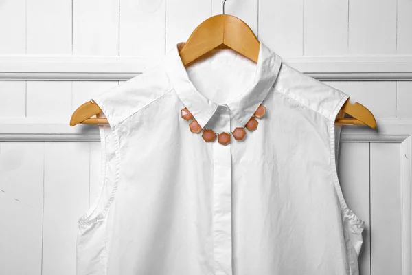 Blouse and necklace on hanger on wall background — Stock Photo, Image