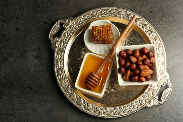 Glass jar and bowl with honey and nuts on gray background — Stock Photo, Image
