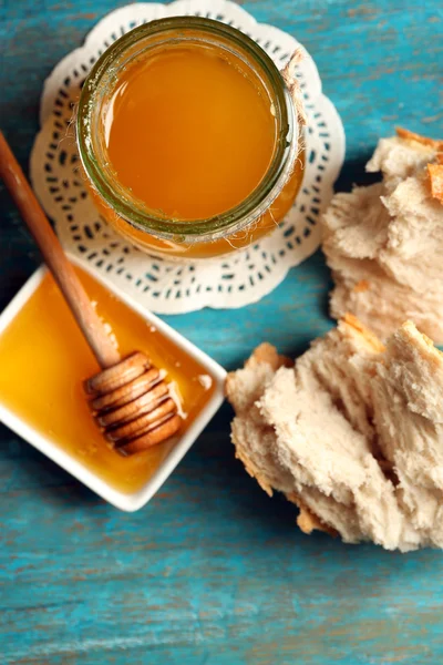 Vaso di vetro e ciotola con miele e pane su sfondo grigio — Foto Stock