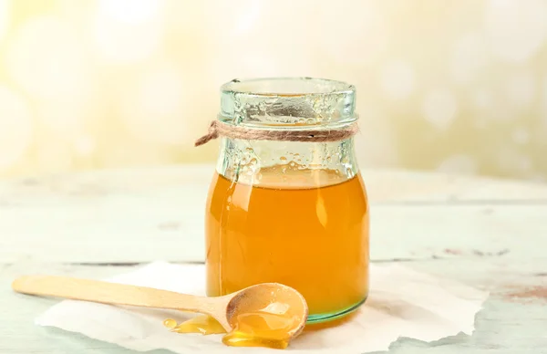 Vaso di miele con cucchiaio di legno su sfondo chiaro — Foto Stock