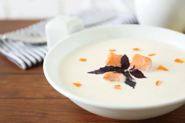 Heerlijke zalm crème soep in witte plaat op houten tafel, close-up — Stockfoto