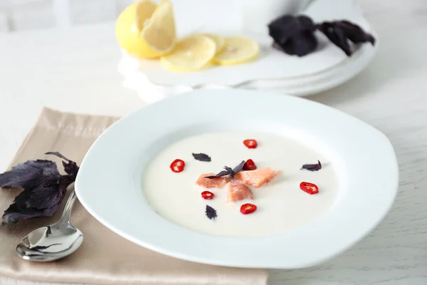 Deliciosa sopa de crema con pescado y albahaca sobre una mesa blanca servida en el restaurante — Foto de Stock