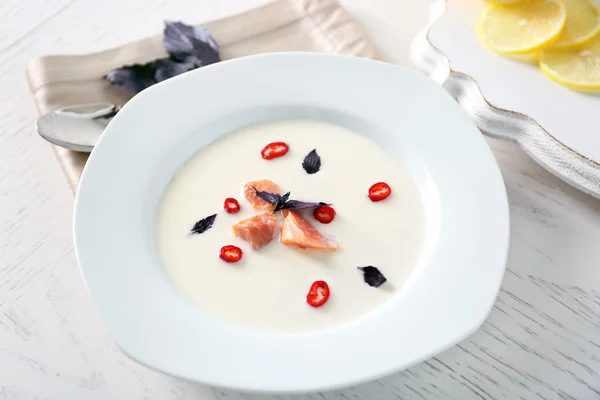 Deliciosa sopa de crema con pescado y albahaca sobre una mesa blanca servida en el restaurante — Foto de Stock