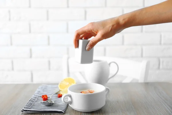 Someone's hand salting salmon cream soup against white brick wall background — Stock Photo, Image