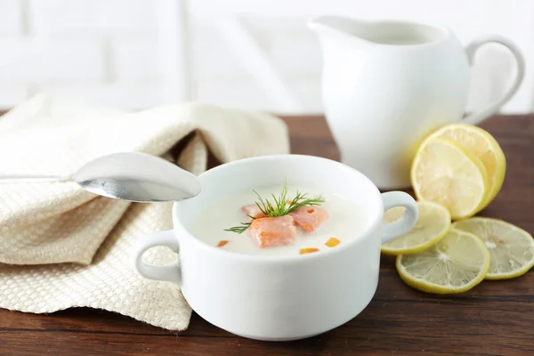 Heerlijke zalm crème soep met lepel op houten tafel, die geserveerd met gesneden citroen en specerijen — Stockfoto