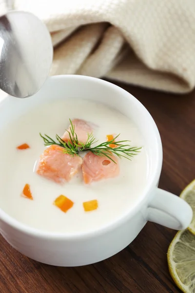 Deliciosa sopa de crema de salmón con cuchara sobre mesa de madera, que se sirve con rodajas de limón y especias — Foto de Stock