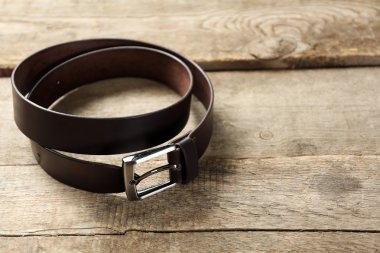 Leather belt with buckle on wooden background clipart