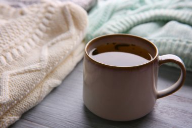 Bir fincan çay ve sıcak giysiler ahşap arka plan üzerinde