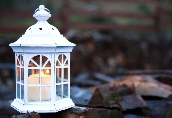 Lantern with candle on stack of firewood — Stock Photo, Image