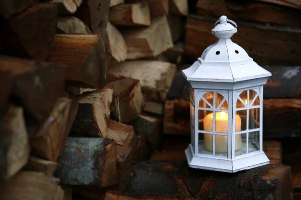 Lantern with candle on stack of firewood — Stock Photo, Image