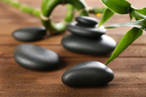 Spa stones and bamboo branch on wooden background — Stock Photo, Image