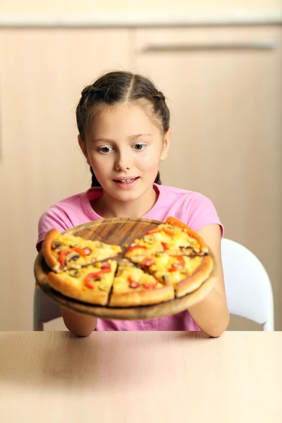 Malá holčička jíst pizzu doma — Stock fotografie