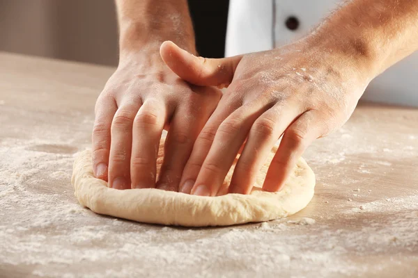 Handen kneden van deeg voor pizza op de houten tafel, close-up — Stockfoto