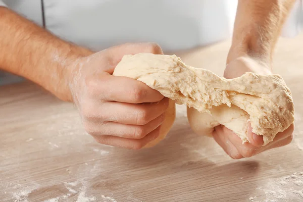 Manos amasando masa para pizza en la mesa de madera, primer plano — Foto de Stock