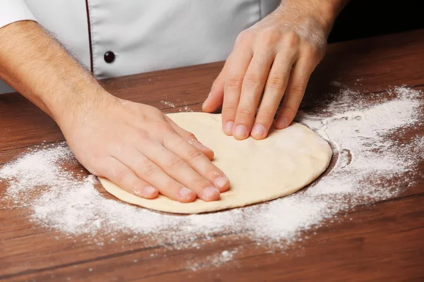 Le mani che preparano la base di pasta per pizza sul tavolo di legno, primo piano — Foto Stock