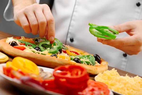 Cook making delicious pizza at the restaurant, close-up