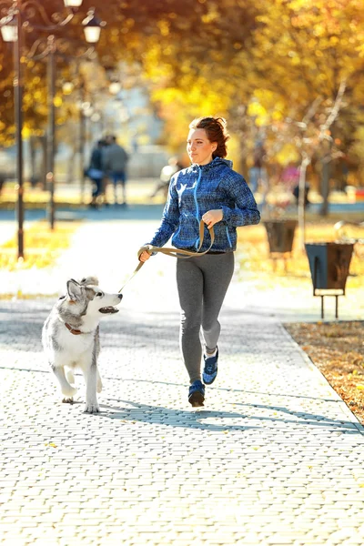 Kocogás a parkban kutyáját, boldog fiatal nő — Stock Fotó