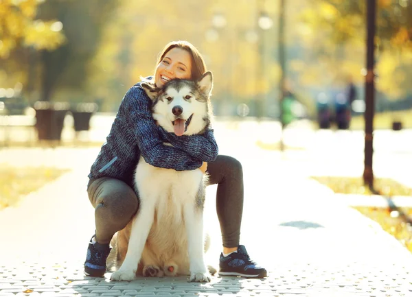Glückliche junge Frau geht mit Hund im Park spazieren — Stockfoto