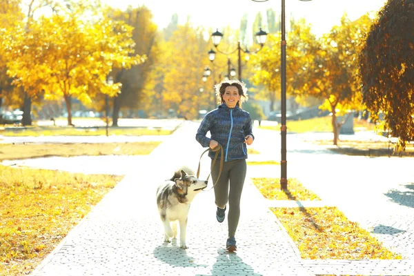Счастливая молодая женщина бегает с собакой в парке — стоковое фото