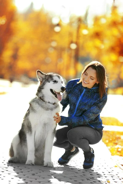 Happy young woman walking with her dog in park — Stock Photo, Image
