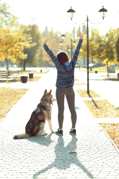 Glückliche junge Frau geht mit Hund im Park spazieren — Stockfoto