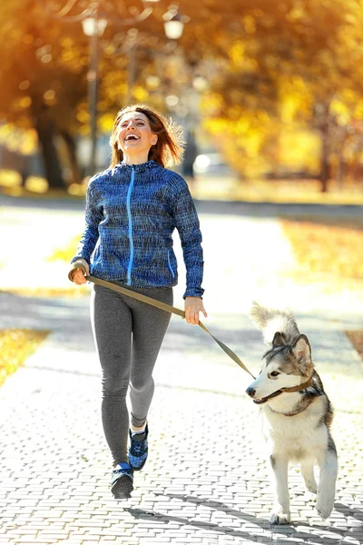 Szczęśliwa młoda kobieta jogging z psem w parku — Zdjęcie stockowe