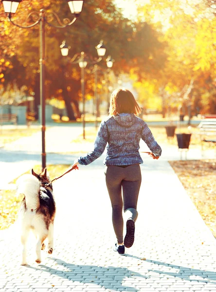 Feliz joven mujer corriendo con su perro en el parque — Foto de Stock