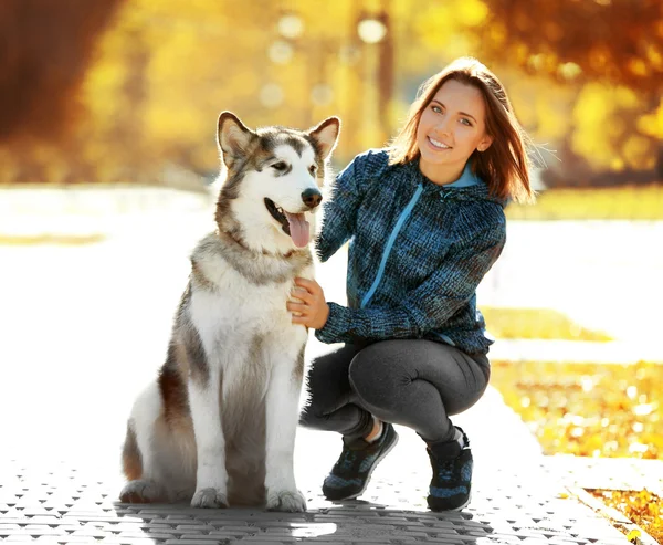 Joyeux jeune femme marchant avec son chien dans le parc — Photo