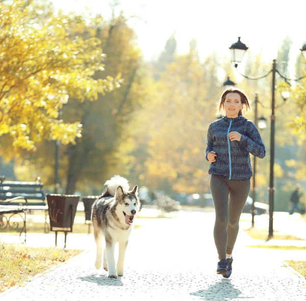 Feliz joven mujer corriendo con su perro en el parque — Foto de Stock