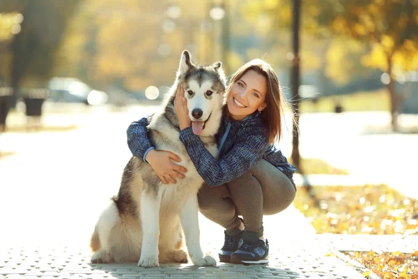 Gelukkig jonge vrouw wandelen met haar hond in park — Stockfoto