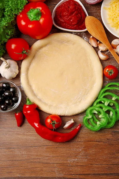 Deeg basis en ingrediënten voor pizza, op de tafel — Stockfoto