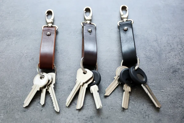 Ключі, прикріплені до шкіряного брелока, на сірому фоні — стокове фото
