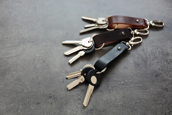 Keys attached to leather keychain , on gray background — Stock Photo, Image