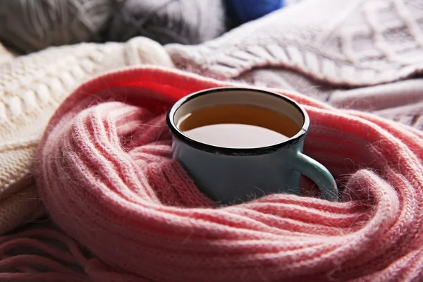 Кружка чая завернутая в шарф и теплая одежда рядом с ним крупным планом — стоковое фото