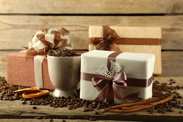 Beaux cadeaux avec des arcs et des grains de café sur fond en bois — Photo