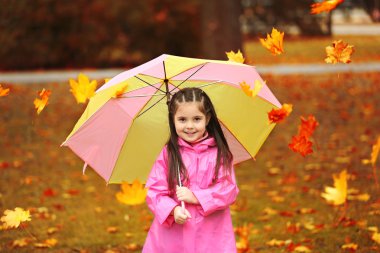 Beautiful little girl with umbrella in park clipart