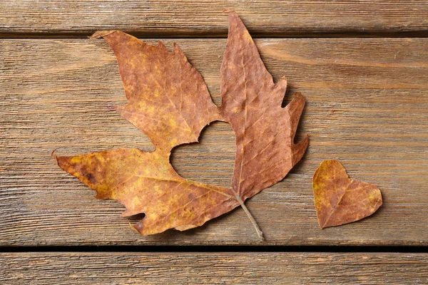 Feuille d'automne séchée avec coeur découpé sur fond en bois — Photo