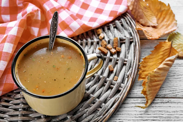 Mug of soup on wicker mat on a table closeup — Stock Photo, Image