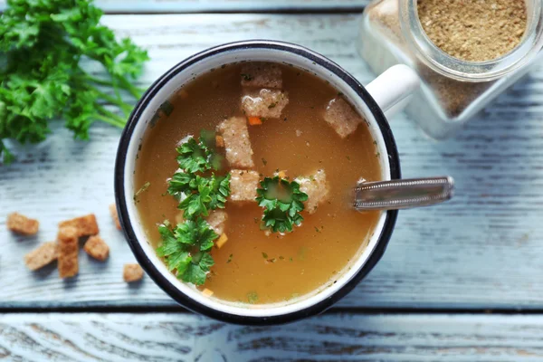 Mug of soup on blue wooden background — Stock Photo, Image