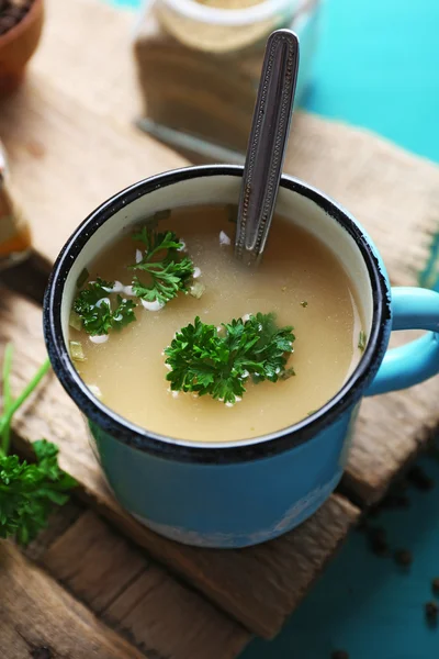 Mug of soup on wooden mat — Stock Photo, Image