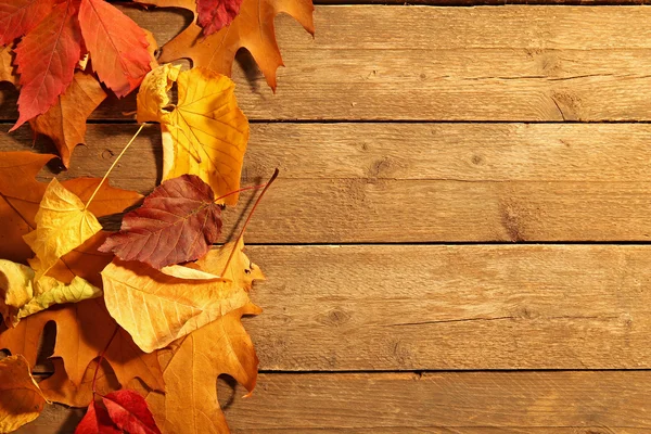 Folhas de outono amarelas e marrons no fundo de madeira — Fotografia de Stock