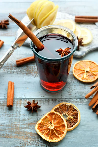 Gustoso vin brulè e spezie, su fondo di legno blu, primo piano — Foto Stock