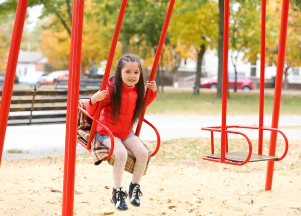 Little girl on swing in city park — Stock Photo, Image