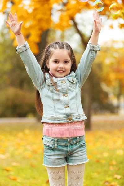 Cute girl playing with soap bubbles in park — Stock Photo, Image