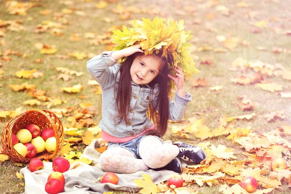 Όμορφο κοριτσάκι με το καλάθι των μήλων που κάθεται στο καρό, εξωτερική — Φωτογραφία Αρχείου