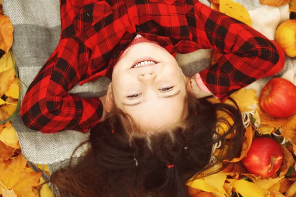 Chica joven feliz acostado en cuadros en el parque de otoño — Foto de Stock