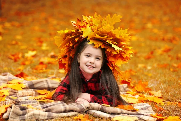 Felice giovane ragazza in gialla corona d'autunno sdraiata su plaid nel parco — Foto Stock