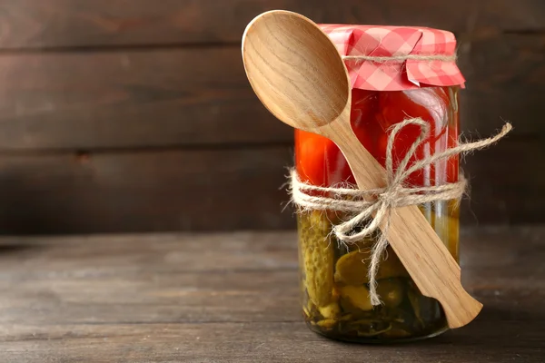 Tarro de pepinos y tomates enlatados sobre fondo de madera — Foto de Stock