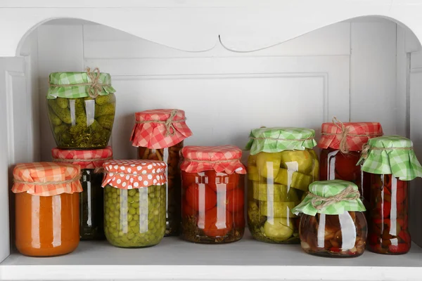 Jars with pickled vegetables and beans on wooden shelf — Stock Photo, Image