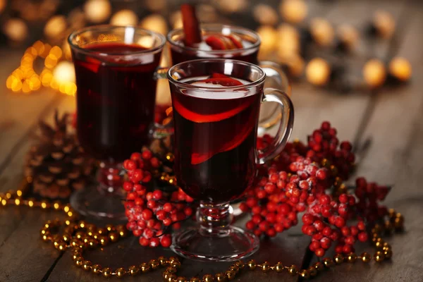 Glühwein mit Gewürzen und Weihnachtsbaum auf Holzgrund — Stockfoto